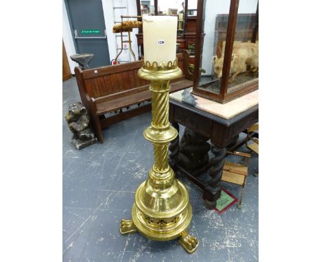 A 1902 MEMORIAL LARGE BRASS FLOOR STANDING CANDLESTICK, THE GALLERIED TOP ON KNOPPED SPIRAL TURNED COLUMN AND THREE PAW FEET.