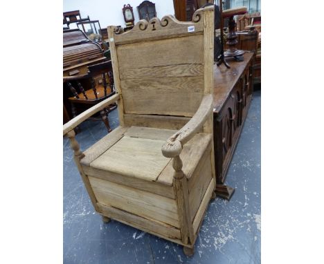 AN 18TH CENTURY OAK LAMBING CHAIR, A SCROLL TOP RAIL TO A PANELLED BACK OVER THE BOX SEAT ON BUM FEET, THE ARMS WITH SCROLLED