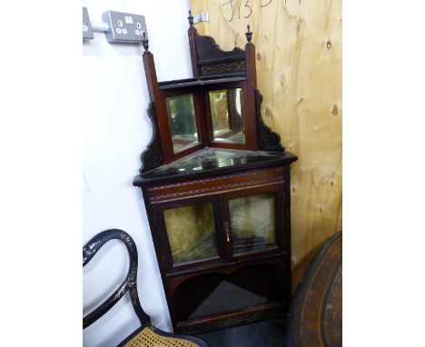 A FLOOR STANDING CORNER CABINET MIRRORED UNDER THE RECESSED EBONISED SHELF TOP, THE GLAZED DOORS BELOW OVER A SHELF WITH PIER