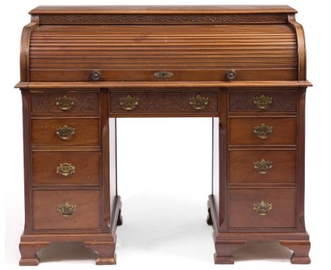 A MAHOGANY TAMBOUR TOPPED DESK the fitted interior with pigeon holes and drawers over nine further drawers, the pedestal base