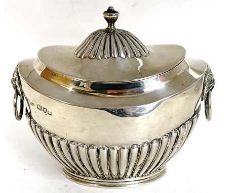 A hallmarked silver tea caddy of oval form, the hinged lid with fluted detail and urn finial, the body having half fluted dec