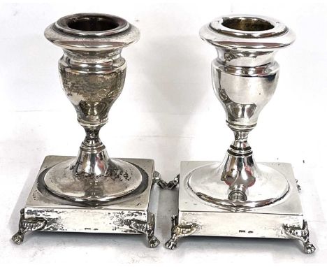 A pair of white metal dwarf candlesticks of urn shape on ring turned stems to a square base on four feet, stamped 925, 10cm t