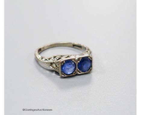   A 1920's white metal (stamped 18ct &amp; plat) and two stone sapphire set ring with carved and single stone diamond chip se