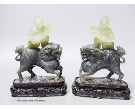   A pair of Chinese bowenite Jade figures of boys riding a qilin, mid 20th century, wood stands