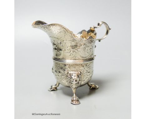   An engraved white metal helmet shaped cream jug, on tripod feet, unmarked, 12.9cm, 9oz.