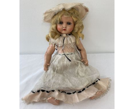 A vintage composite doll with closing eyes, painted lips, blonde hair and cryer box.  