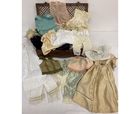 A wooden box containing a quantity of vintage and modern dolls dresses and undergarments.  To include bodices, slips, vests a