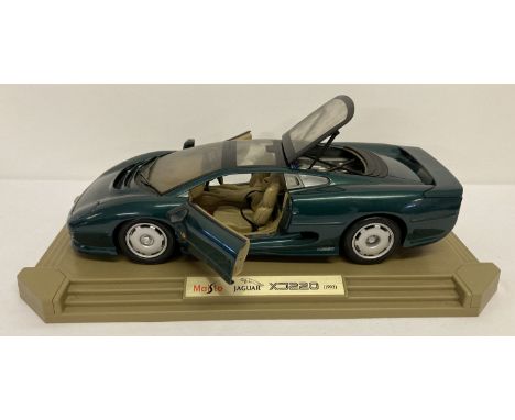 A 1:18 scale diecast Jaguar XJ220 (1992) by Maisto on a display plinth.  In British racing green. With opening doors, bonnet 