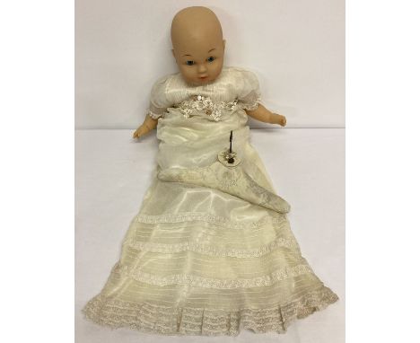 A modern baby doll with cloth body and vinyl head, hands and body, in a vintage christening gown.  Lace and floral detail to 