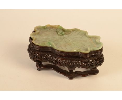 A Chinese mottled green, rust and white jade shallow tray like dish, carved as a spreading lotus leaf with incised and raised
