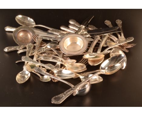 A suite of German ornate silver coloured metal cutlery comprising a tea strainer, a sauce ladle, six coffee spoons, six desse