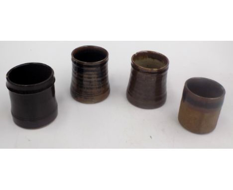 Four Leach pottery tenmoku glazed mugs, heights 8cm, 9cm, 9.1cm and 9.3cm.