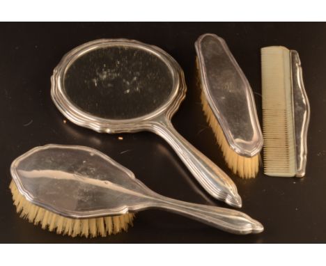 A four piece silver mounted dressing table set comprising two brushes, a hand mirror and a comb, each engraved with the lette