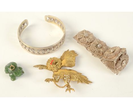 A carved jade frog, a filigree bracelet, an eastern silver bracelet and one other piece. 