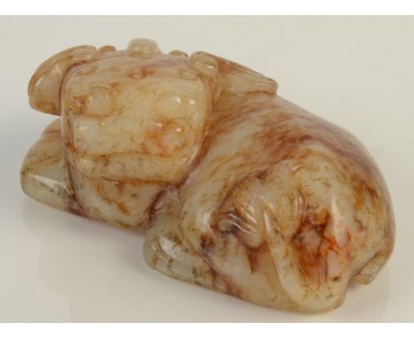 A Chinese white and brown striated jade pebble carved as a reclining Buddhist Dog of Fo, mid-Ming period, height 2.1cm, lengt