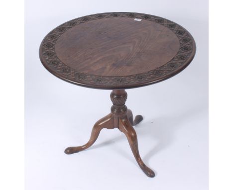 A George III mahogany tripod table, the circular tilt top, with rosette carved border, above a bird cage action on a fluted b