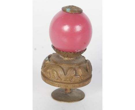 A Chinese gilt metal and pink glass hat finial, circa 1900, with shou and stylised dragon decorated mounts, height 6.2cm.   C
