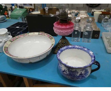 A cast iron base oil lamp with pink glass resovoir, large dressing table bowl and Doulton chamber pot.