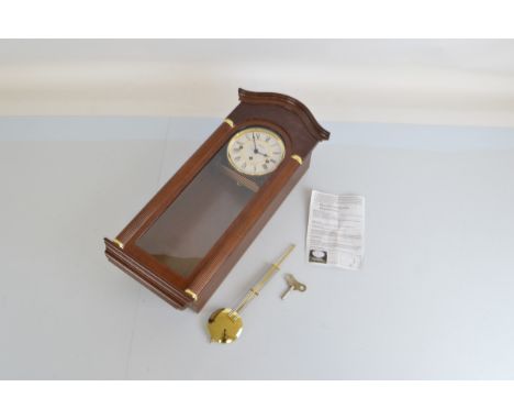 A Hermle wall clock, with pendulum, key and instructions. 63cm long.