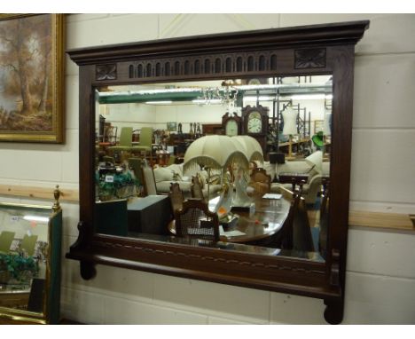 AN OLD CHARM OAK FRAMED BEVELLED WALL MIRROR, with carved detail and lower shelf