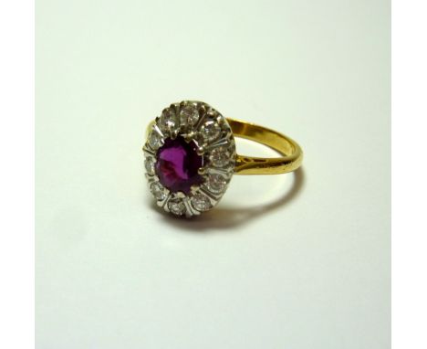 A RUBY AND DIAMOND CLUSTER RING, with central oval ruby within a surround of brilliant cut diamonds to the plain tapered shan