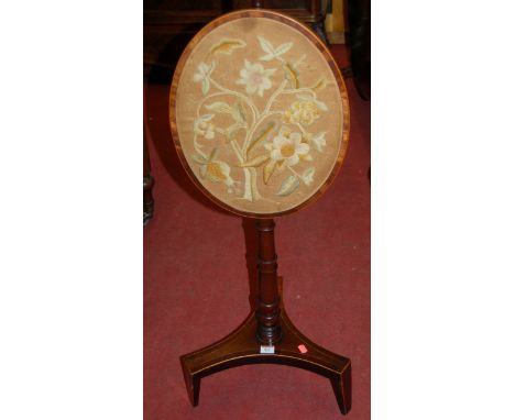 An early 19th century mahogany and rosewood crossbanded polescreen having oval floral embroidered adjustable panel
