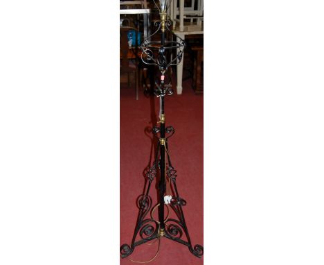 A late Victorian black painted wrought iron and brass standard lamp with telescopic action