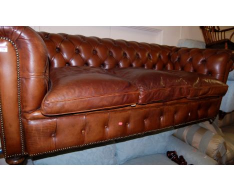A good quality contemporary chocolate brown leather three-seater button back Chesterfield having brass studding and on bun fo