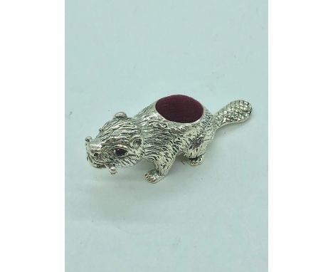 A silver pincushion in the form of a beaver with ruby eyes