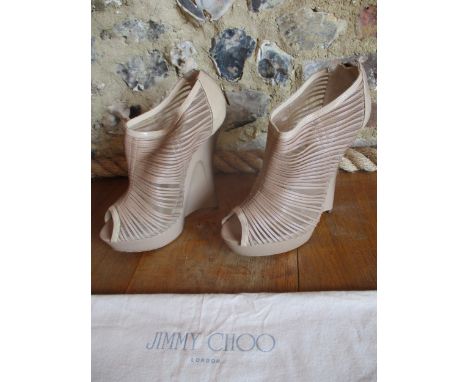 A pair of Jimmy Choo 6" wedge heel, open toe, ankle zipped shoes in a light beige patent with a mesh throat and gold hombre e