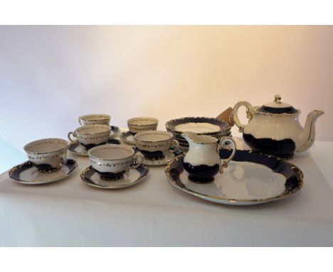 A ZSolnay Hungarian porcelain tea set, on a white ground with cobalt blue borders and gold rims. 