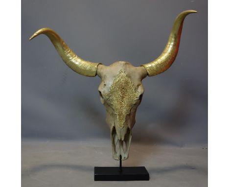 A faux bison skull with gilt painted horns, on stand, H.72 W.78cm 