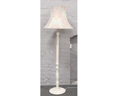A white painted column standard lamp and floral shade. 