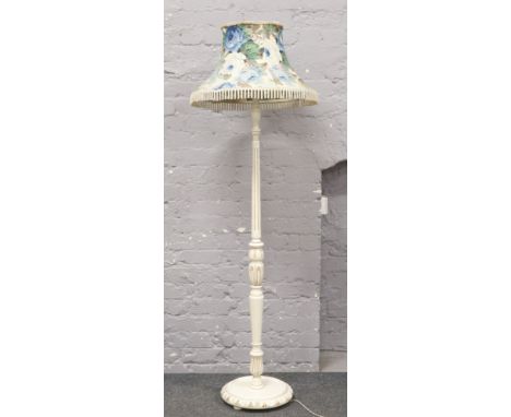 A white painted standard lamp with floral shade. 