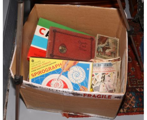 A box of miscellaneous to include childs sewing machine, two vintage board games, cigarette card album, old recipe magazines 