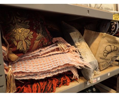 Shelf of linen throws patchwork quilt and cushions 