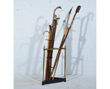 A brass triangular stick stand with thirteen homemade sticks, mostly with horn and antler tops, two copper horns, hip flasks 