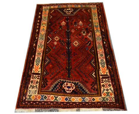 A Gabbeh wool rug, ruby field with geometric design, enclosed by cream patterned borders 170 x 107cm.