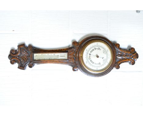 Carved oak aneroid barometer, scrolled and foliate outlines, thermometer over, 74cm.