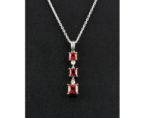 An 18ct white gold pendant and chain set with princess cut rubies and brilliant cut diamonds, L. 2.7cm.