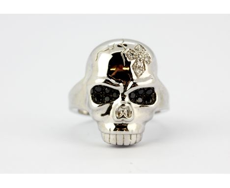 A 9ct white gold skull shaped ring set with diamonds and fancy black diamonds, (N).