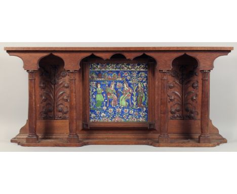 A LARGE PERSIAN QAJAR GLAZED POTTERY TILE inset within a carved oak overmantle, the tile depicting seated figures with attend