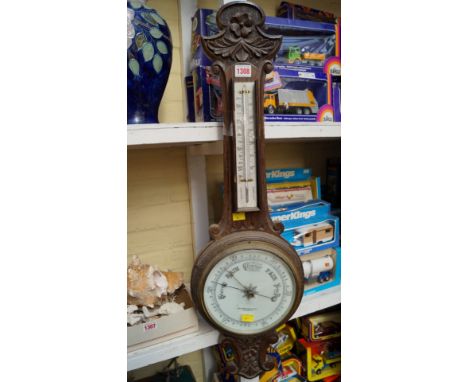An early 20th century carved oak aneroid wheel barometer, the circular dial inscribed 'John Barker & Co Ltd, Kensington'.