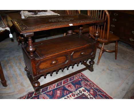 A reproduction Oak Monk's Bench, having rectangular moulded edge carved top/back, on turned supports forming arms, and lower 