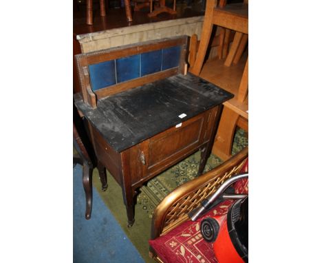 A 1940's oak Wash Stand, moulded frame tile back, black marble top over single panel central door with iron tear drop handles