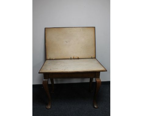 An Edwardian oak card table on pad feet, lacking baize interior