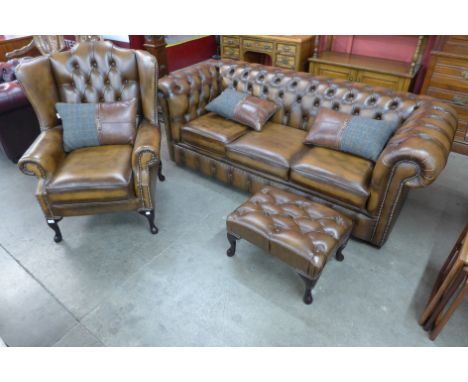 A Chesterfield brown leather three piece lounge suite, comprising; sofabed settee, wingback armchair and a pouffe 