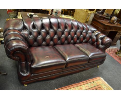 A contemporary Thomas Lloyd, Chesterfield style three seater sofa, burgundy button back leather upholstery; a matching armcha