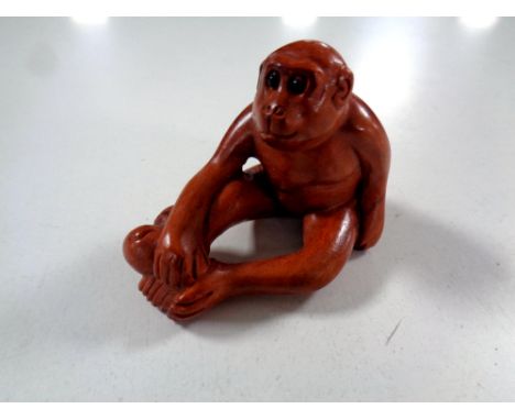 A carved Chinese hardwood netsuke, monkey with fruit  