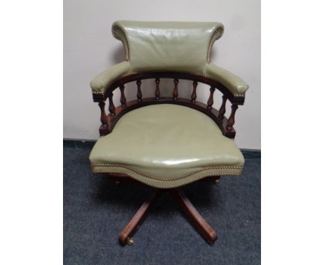 A captain's swivel desk chair upholstered in a light green leather 